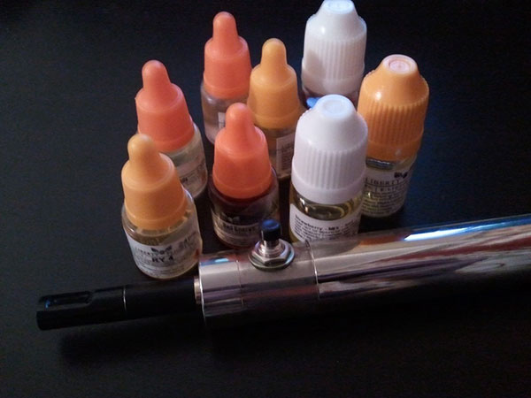 An e-cigarette and several e-liquid bottles
