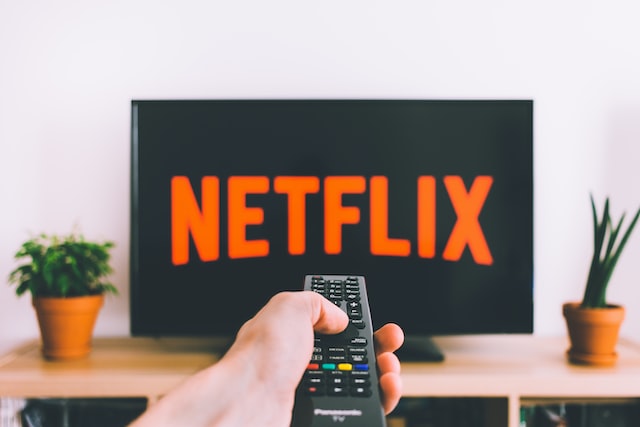 A person holding the remote in Hand to Play Netflix on Smart TV